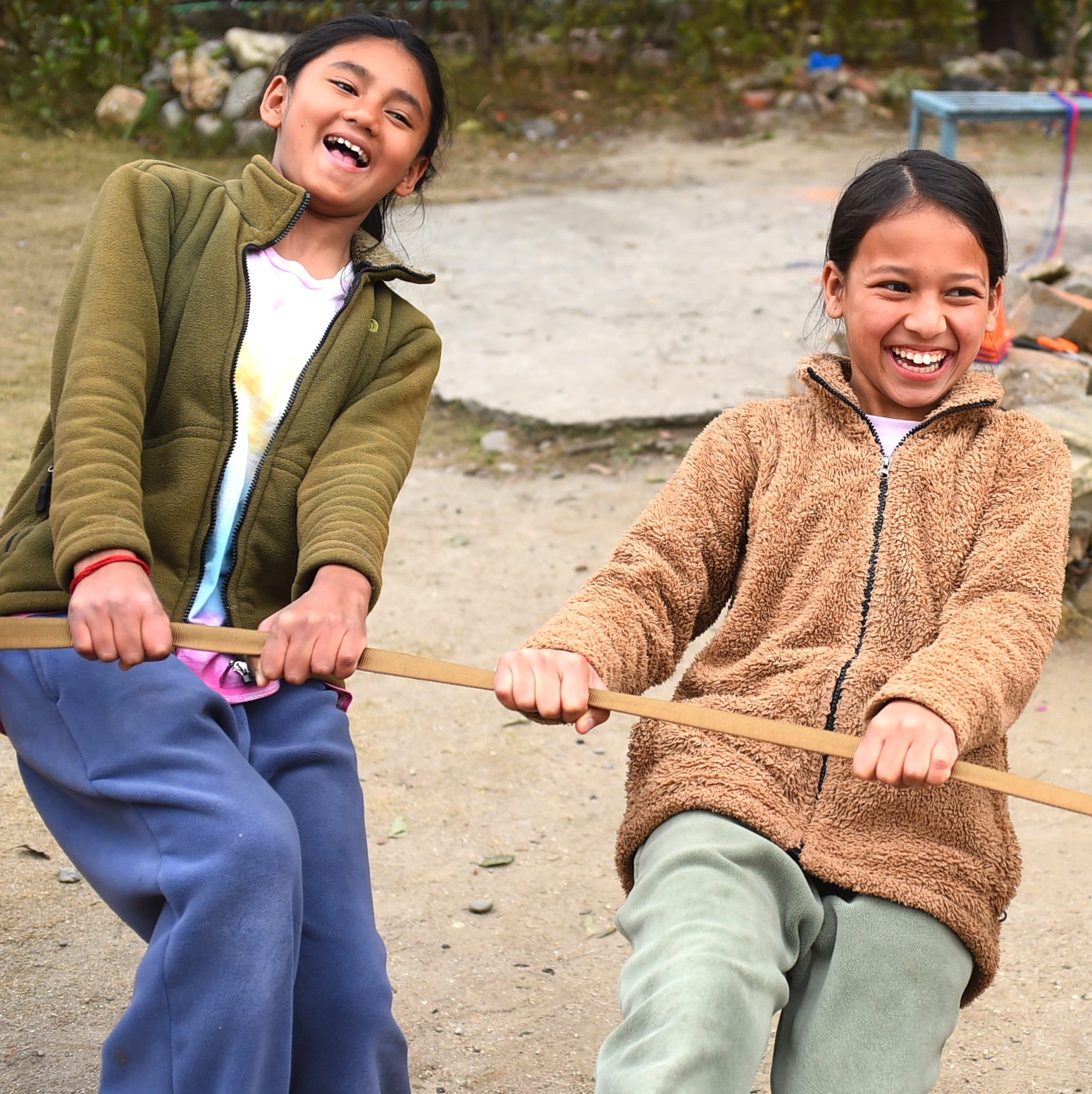 Two girls laughing while playing together outdoors