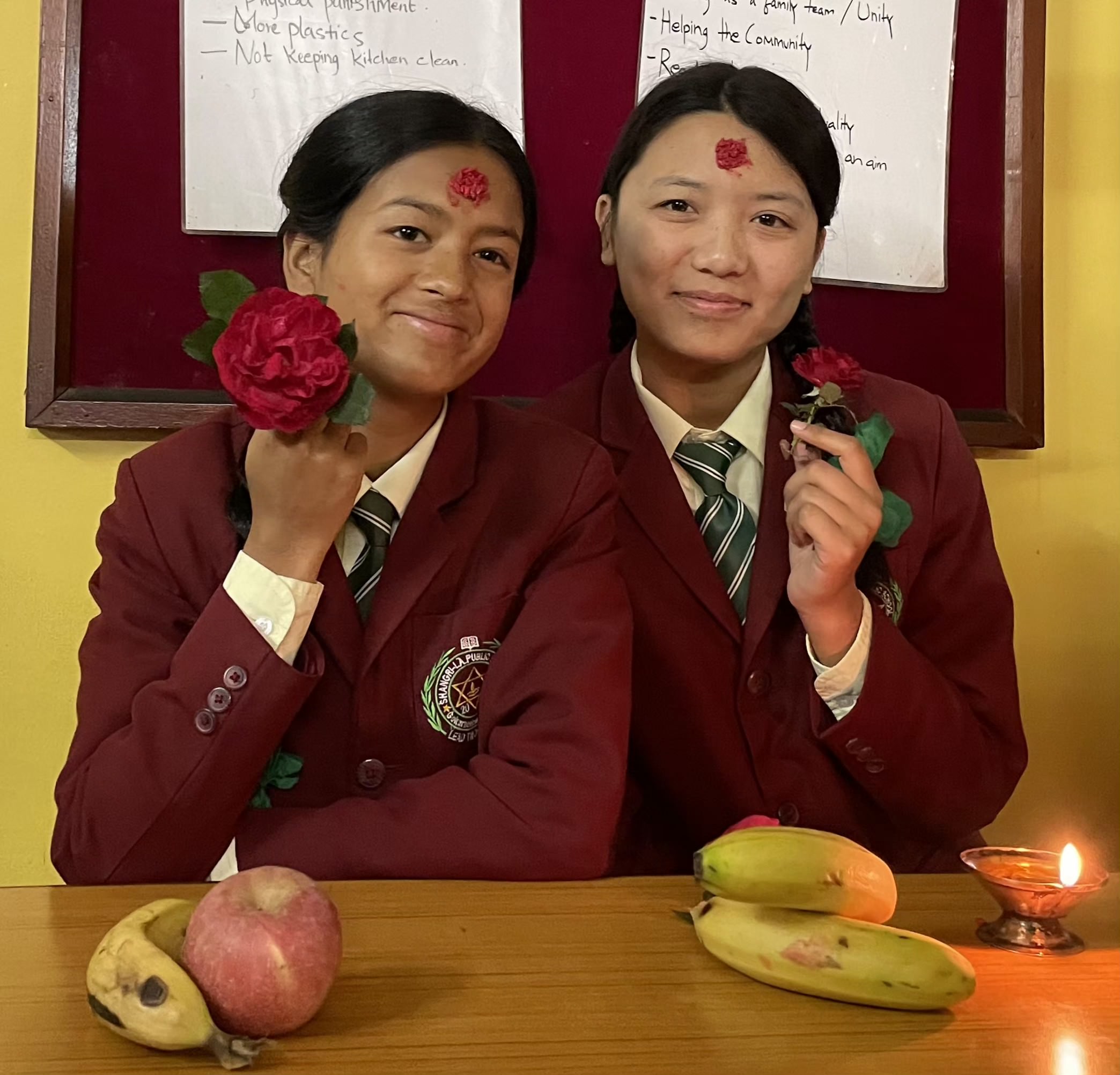 Two students in school uniforms holding flowers