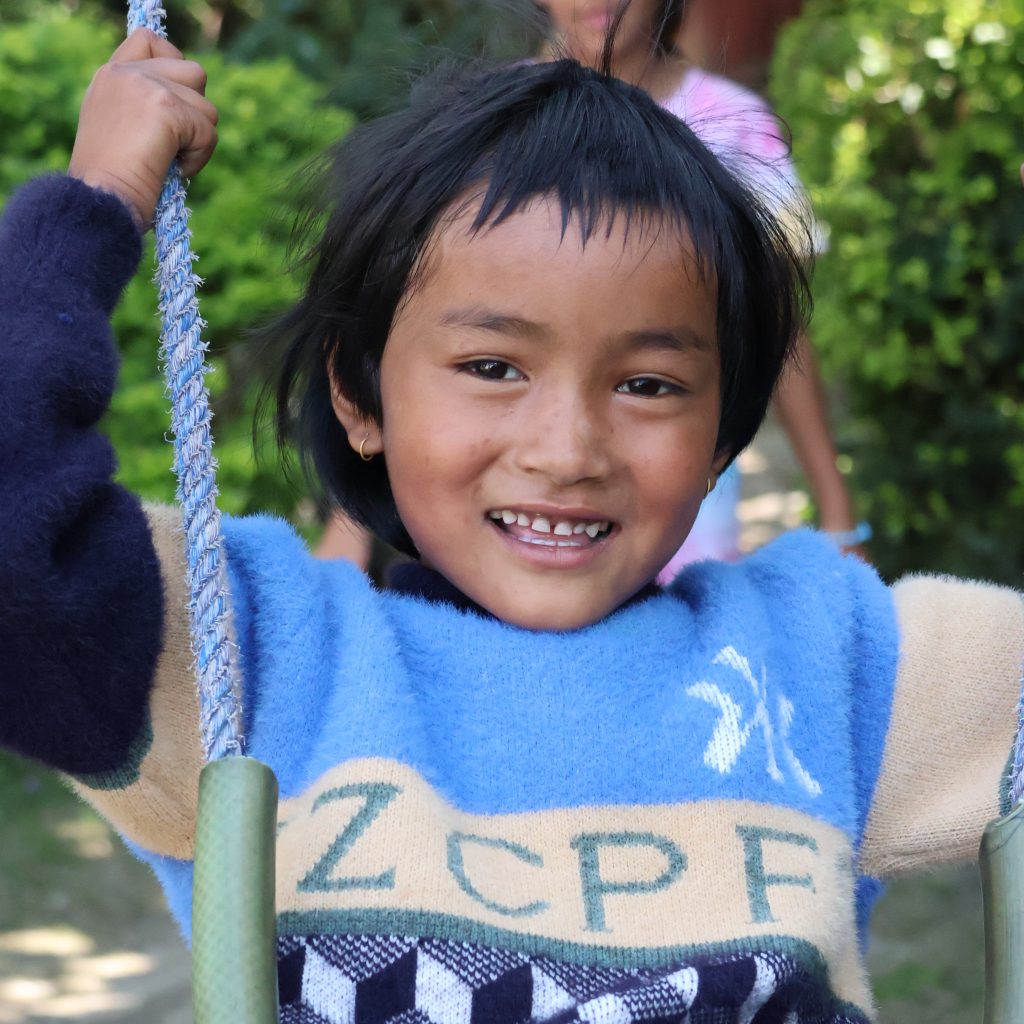 Pratikshya smiling on a swing in the House garden